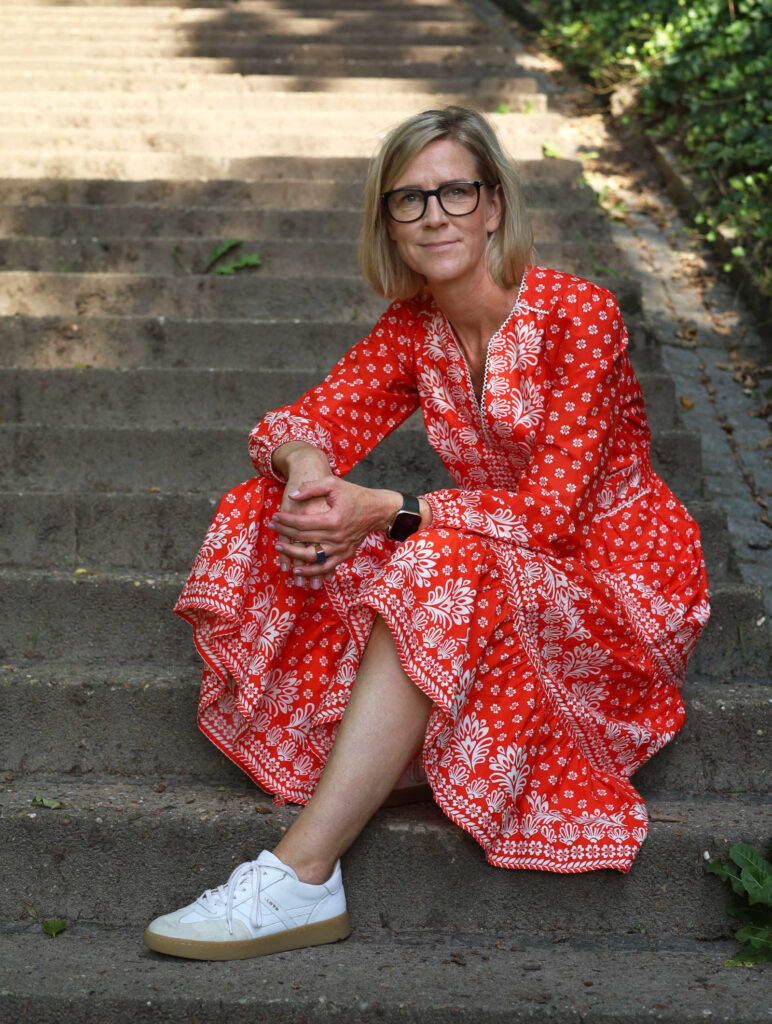 Petra Seidler, auf einer Treppe sitzend