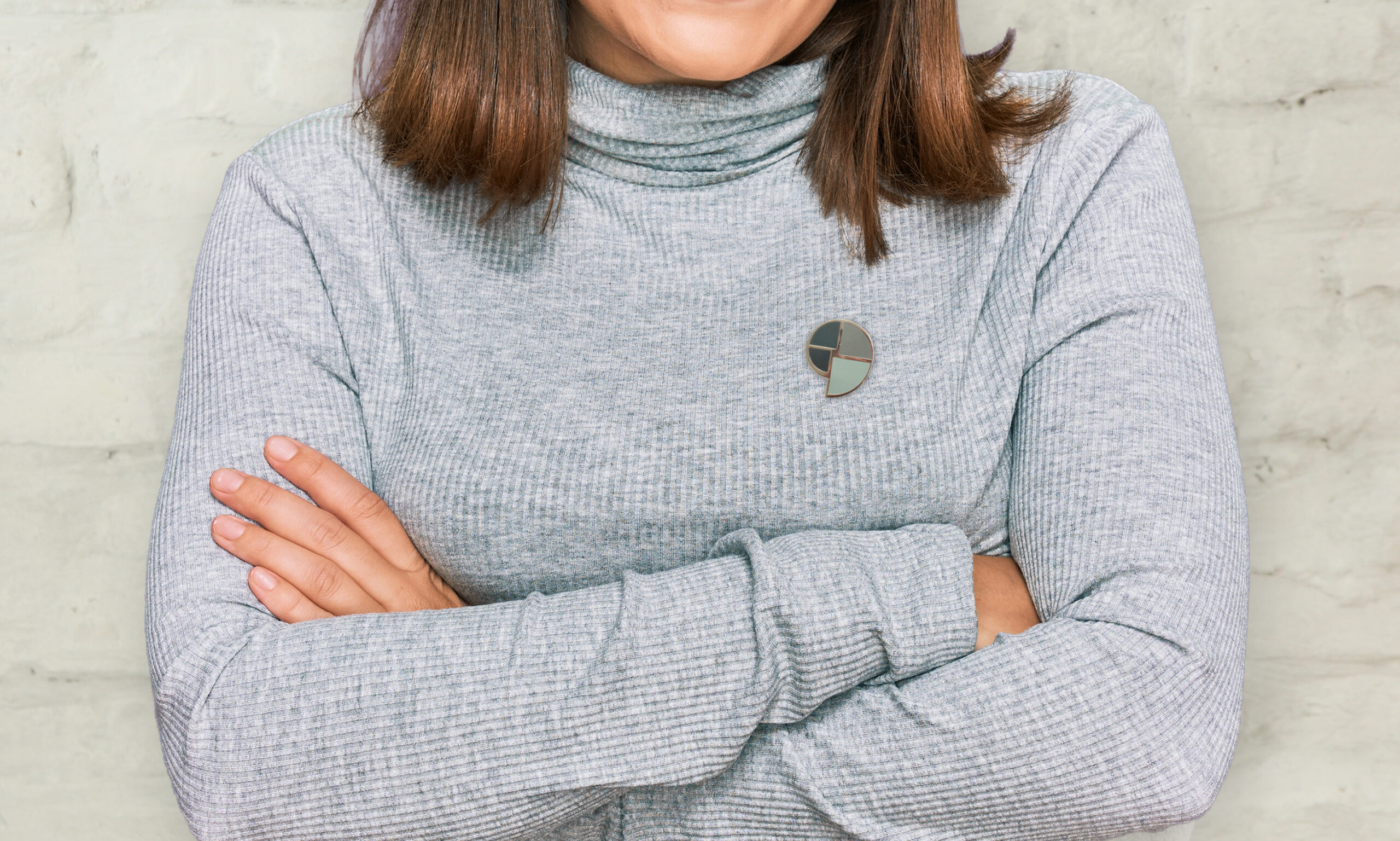 Frau trägt einen TRAUDO®-Pin in Grau am Pullover
