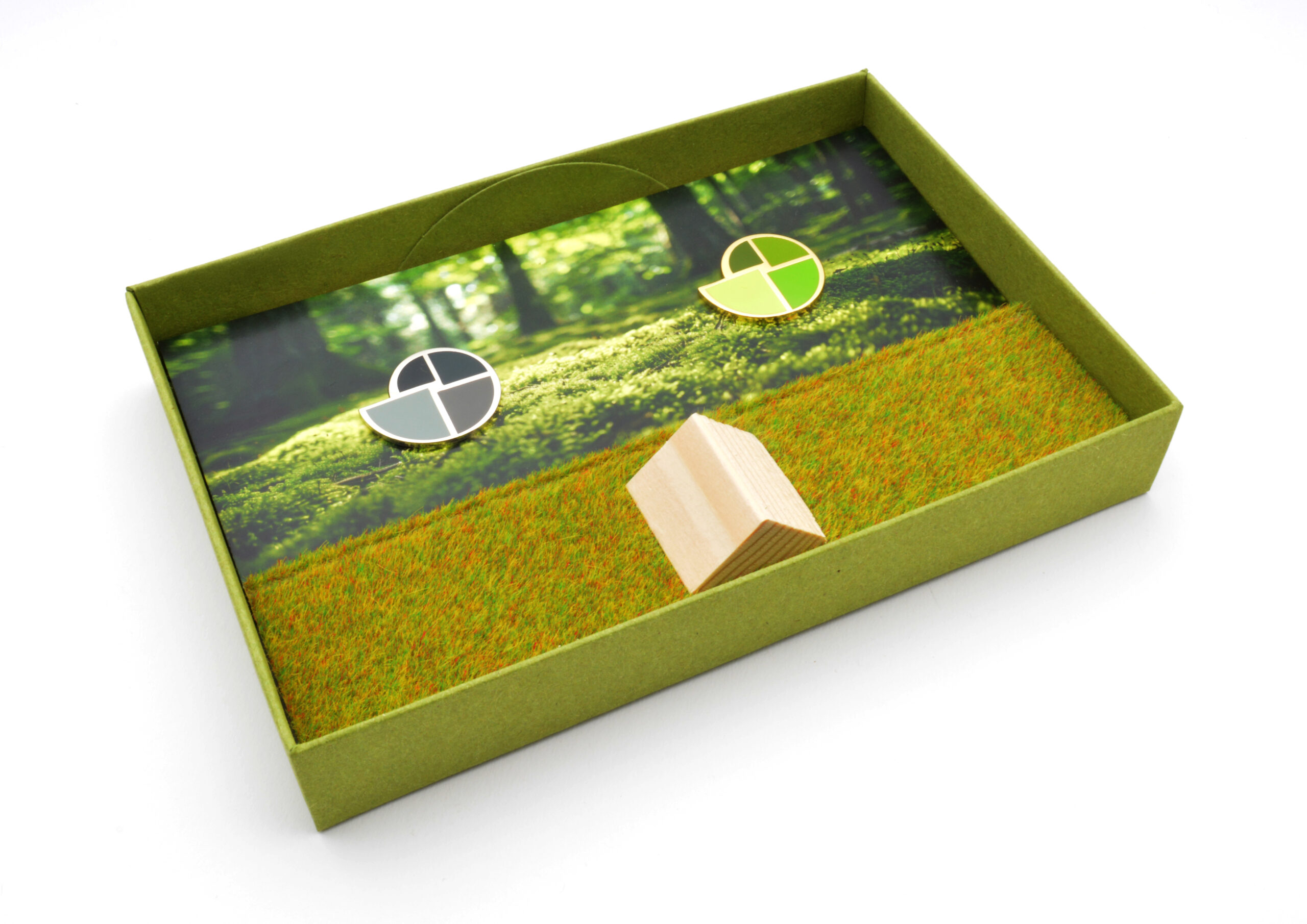 Blick ins Innere der grünen TRAUDO®-Verpackung mit Ansteckern in Grün und Grau